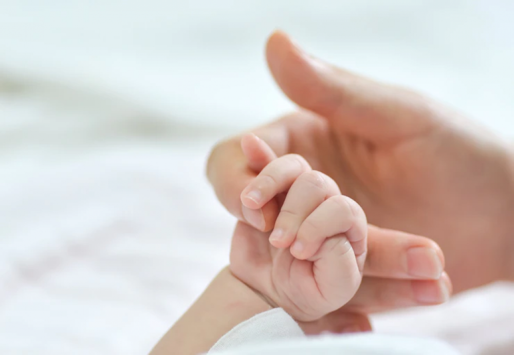 bayi memegang tangan ibu